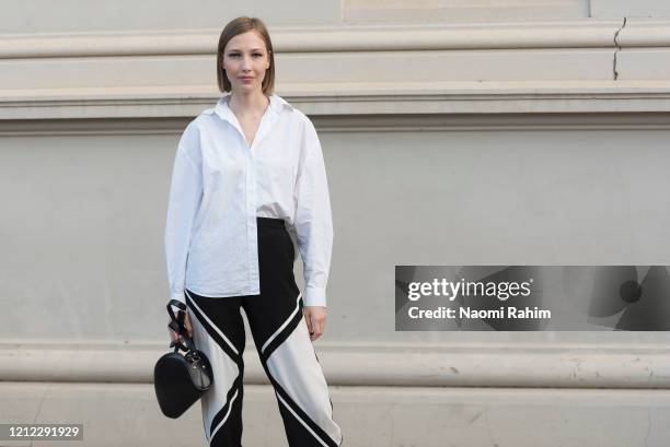 An off-duty model poses in a white shirt and black and white geometric print pants ahead of Runway 1 at Melbourne Fashion Festival on March 11, 2020...