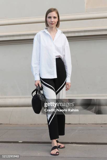 An off-duty model poses in a white shirt and black and white geometric print pants ahead of Runway 1 at Melbourne Fashion Festival on March 11, 2020...