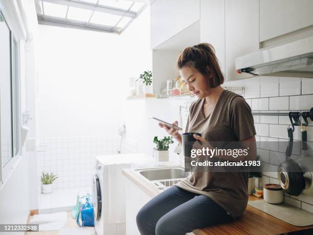 young woman sitting in cozy kitchen and working on her mobile. - cooker dial stock pictures, royalty-free photos & images