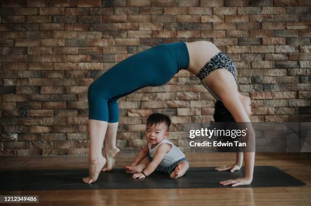 an asian chinese female yoga instructor with bridge pose while her son looking at camera