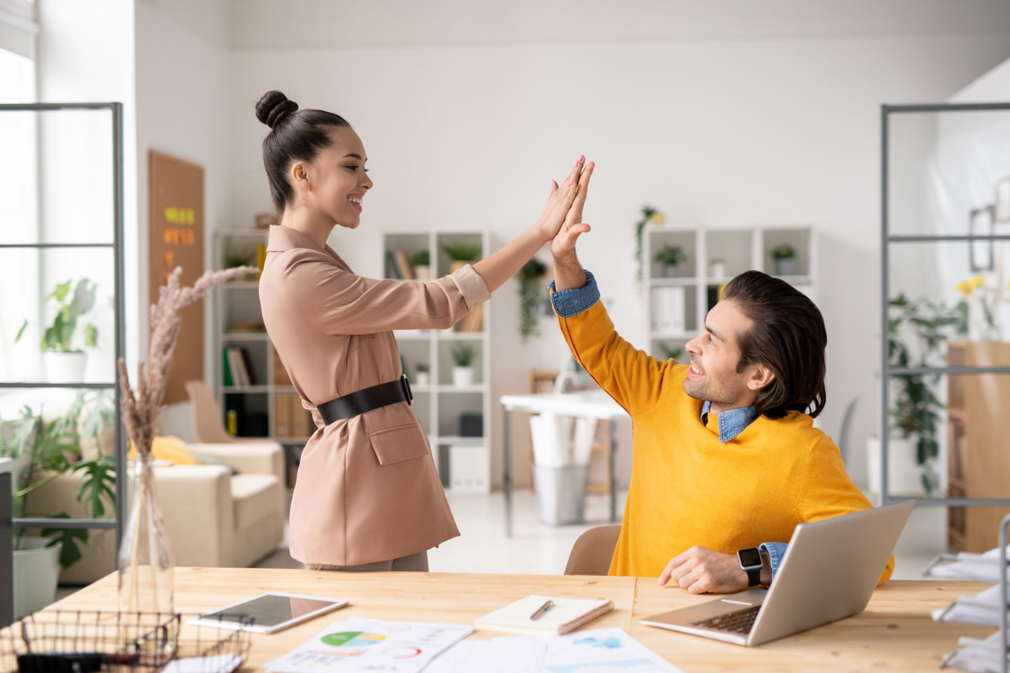 Two happy young successful colleagues giving each other high five Two happy young successful colleagues giving each other high five