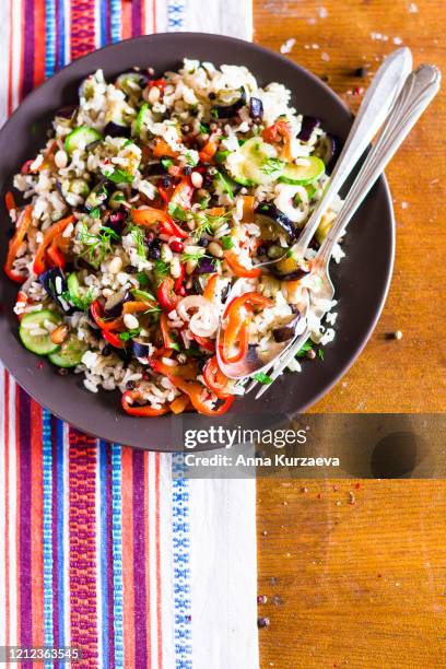 plate of warm salad with brown rice, roasted eggplant, zucchini, red and green bell pepper, mushroom, onion, top view - brown rice stock pictures, royalty-free photos & images