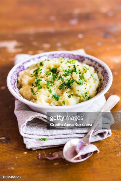 bowl of mashed potatoes with baked garlic, butter and fresh chopped parsley on a wooden table, selective focus - mashed potatoes stock-fotos und bilder