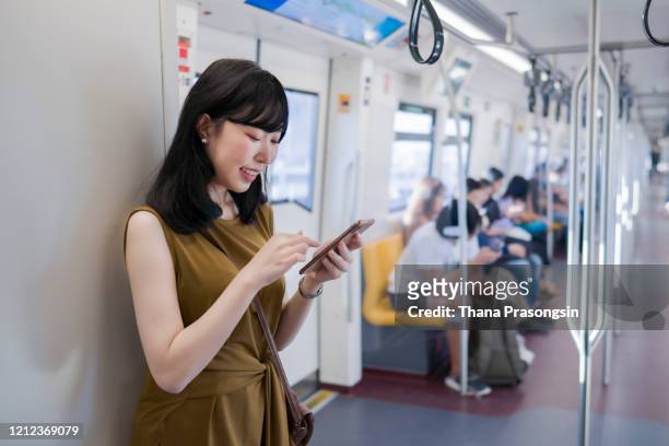 young woman using mobile phone in the subway station - very young thai girls stock pictures, royalty-free photos & images