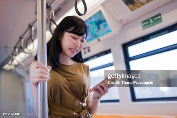 woman uses mobile app while riding commuter train - pole positie fotografías e imágenes de stock