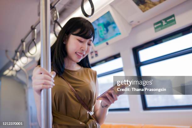 woman uses mobile app while riding commuter train - 通勤電車 ストックフォトと画像
