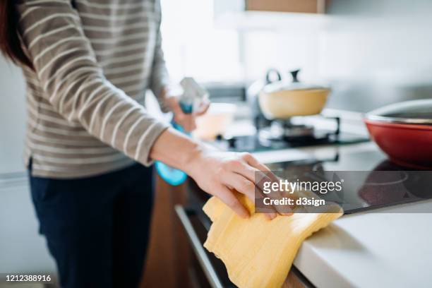 cropped shot of a young woman cleaning the kitchen counter with cleaning spray and cloth at home during the day - housecleaning only women stock pictures, royalty-free photos & images