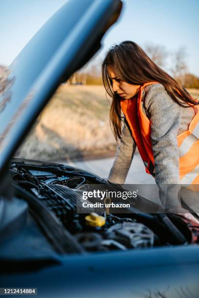 woman looking at broken cars motor - vehicle breakdown stock pictures, royalty-free photos & images