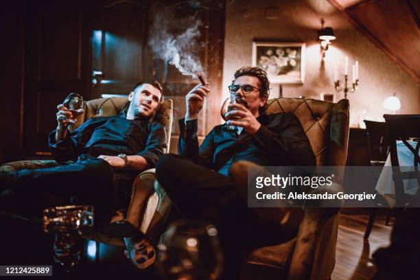 maffia familie vader en zoon genieten van goede cognac met sigaren en gesprek - cognac stockfoto's en -beelden