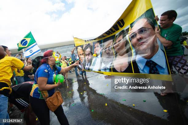 Supporters of Brazilian President Jair Bolsonaro throw water balloons at a banner with photos Alexandre de Moraes, minister of Brazilian Supreme...