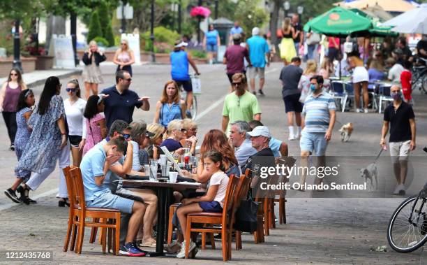 Visitors to Park Avenue in Winter Park, Fla., dine al fresco on the street as restaurants and shops opened in the popular dining district, with Phase...