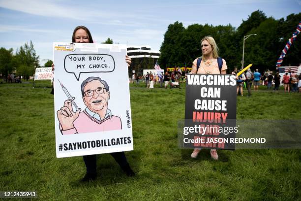 Two women hold anti-vaccination signs during a protest against Governor Jay Inslee's stay-at-home order outside the State Capitol in Olympia,...