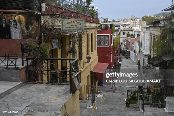 Man walks by closed cafes and taverns at the touristic Plaka district, neighbouring with Koukaki district in Athens on April 14 during a lockdown...
