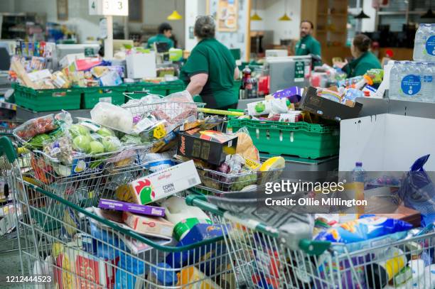 Workers collect items to restock the empty shelves in a London Morrisons store as panic-buying over coronavirus continues on March 14, 2020 in London...