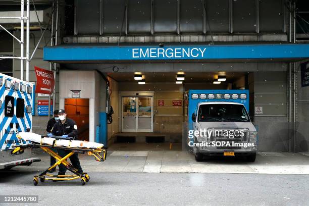Emergency Medical Technicians move a gurney out of the emergency entrance into an ambulance at Mt. Sinai-Beth Israel Hospital amid coronavirus...