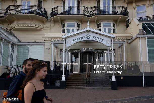 People walk past the famous Grand Hotel on May 9, 2020 in Brighton, England. On the 24th March 2020 the hotel closed until further notice, it said in...
