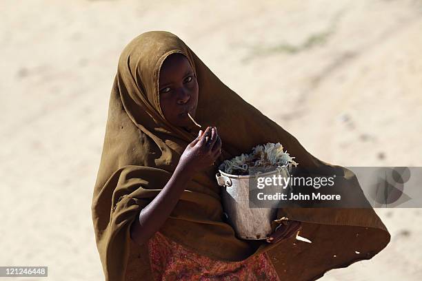 Somali girl takes home a pot of pasta from a feeding center on August 16, 2011 in Mogadishu, Somalia. The center, which serves up cooked meals...