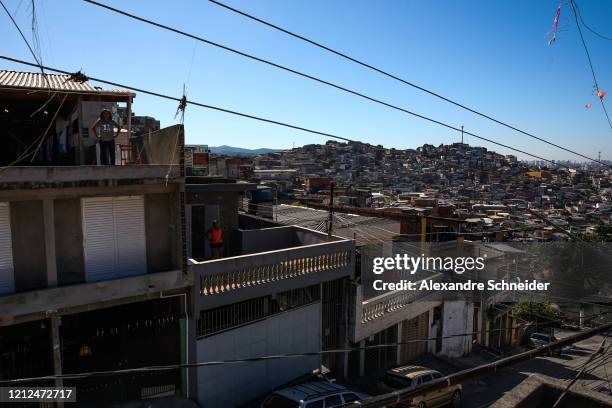 Residents of Brasilandia exercise as Ivan Pereira do Nascimento, 39 years old, conducts training sessions from the roof of his house amidst the...