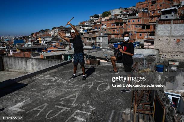 Ivan Pereira do Nascimento, 39 years old, conducts training sessions from the roof of his house to residents of Brasilandia amidst the coronavirus...