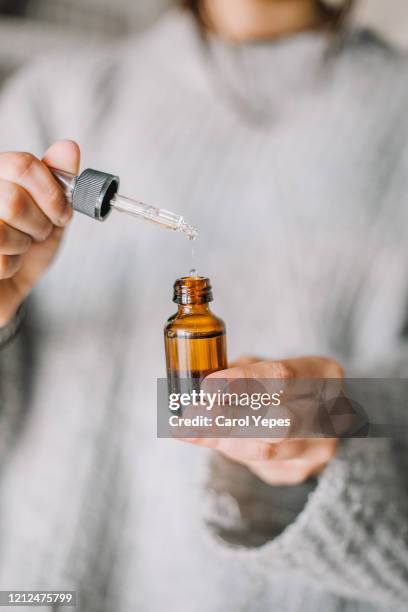 woman hands holding pipette of essential oil - homeopatía fotografías e imágenes de stock