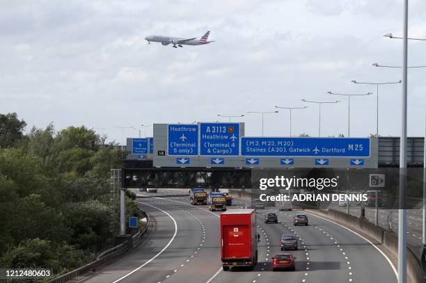 Traffic is seen on the M25 motorway as a plane flies overhead during the morning rush hour near Heathrow Airport in west of London on May 11, 2020. -...