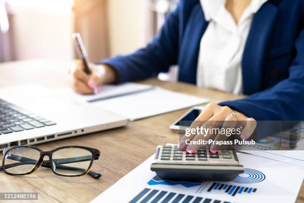 business woman using a calculator to calculate the numbers on his desk in a office - bill legislation stock pictures, royalty-free photos & images