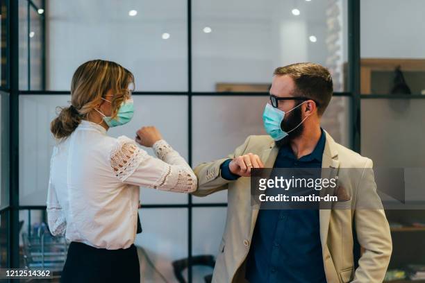 zakenmensen groet tijdens covid-19 pandemie - griepmasker stockfoto's en -beelden