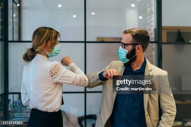 zakenmensen groet tijdens covid-19 pandemie - beschermend masker werkkleding stockfoto's en -beelden