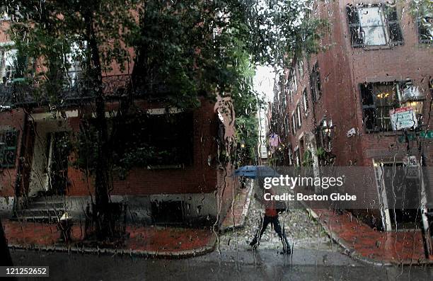 Pedestrian walks under an umbrella on West Cedar Street past Acorn Street on Beacon Hill in the rain.