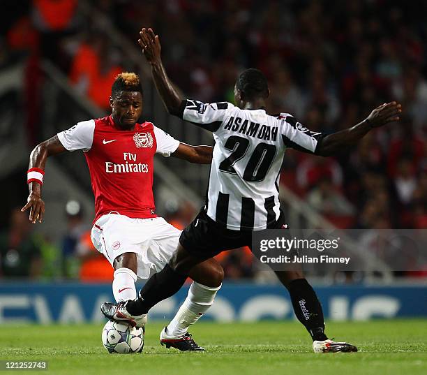 Alex Song of Arsenal and Kwadwo Asamoah of Udinese battle for the ball during the UEFA Champions League play-off first leg match between Arsenal and...