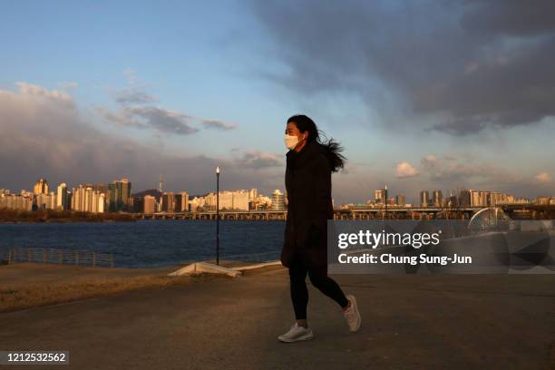 South Korean woman wears a mask to protect herself from the coronavirus walks along the Han River park on March 15, 2020 in Seoul, South Korea....