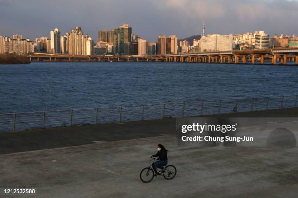 South Korean woman wears a mask to protect herself from the coronavirus ride bicycle at the Han River park on March 15, 2020 in Seoul, South Korea....