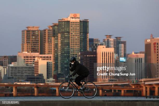 South Korean man wears a mask to protect himself from the coronavirus ride bicycle at the Han River park on March 15, 2020 in Seoul, South Korea....