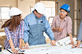 Asian engineers were consulted together and plan in construction site, engineering concept