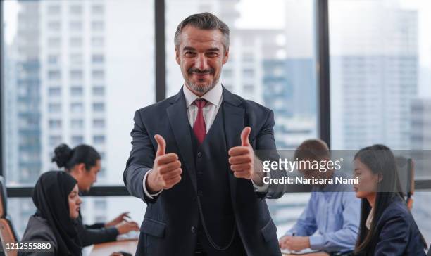 ceo businessman wearing suit with success sign doing positive gesture with hand, thumbs up smiling and happy. cheerful expression and winner gesture. successful business team. - daumen stock-fotos und bilder