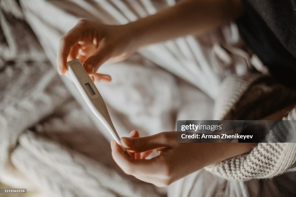 Sick young woman holding thermometer