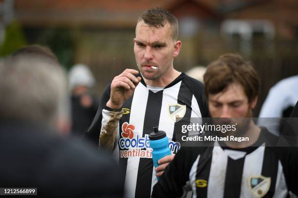 Player smokes a cigarette during the half time team talk during Sunday league football between Syston Brookside FC and Shepshed Oaks FC on March 15,...