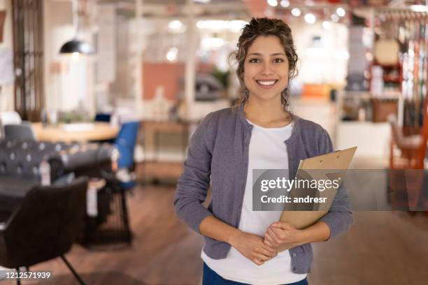 gelukkige verkoopster die meubilair bij een meubilairopslag verkoopt - furniture store stockfoto's en -beelden