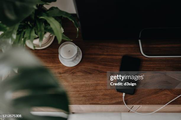directly above shot of a smartphone getting charged with power cable on a cabinet in the living room - phone still life stock pictures, royalty-free photos & images