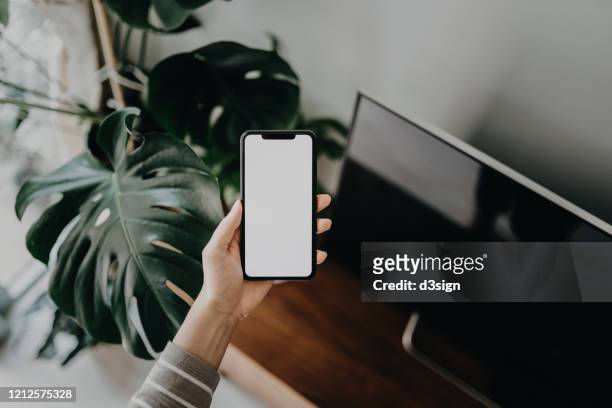 cropped shot of a woman's hand using smartphone in the living room at home - human hand stock pictures, royalty-free photos & images