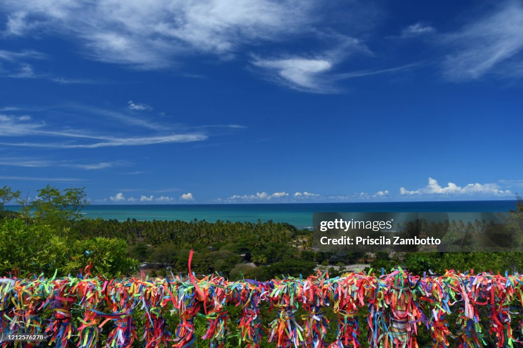 Colorful ribbons and the view from the lookout behind the Church of Nossa Senhora da Ajuda in Arraial d'Ajuda, district of the Brazilian municipality of Porto Seguro, Bahia, Brazil.