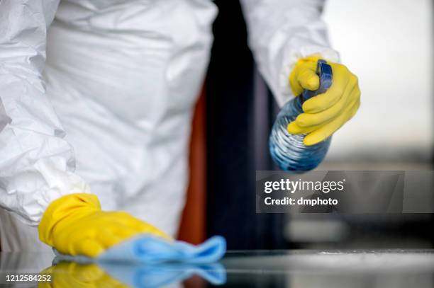 covid-19 wiping down surfaces. woman with gloves and disinfectant wipe sanitizing the desk to prevent germs and bacteria infections" - decontamination stock pictures, royalty-free photos & images