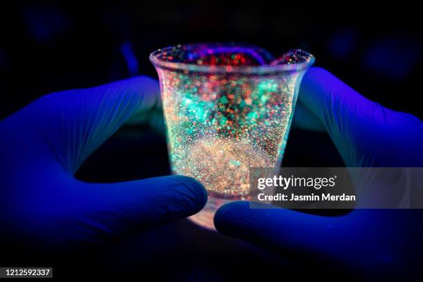 hand holding bacterial tube under uv light - glass beaker stock pictures, royalty-free photos & images