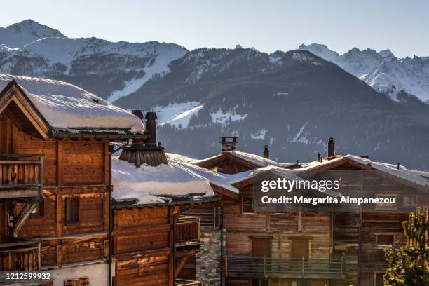 roofs covered in snow and mountains in the background - verbier ストックフォトと画像