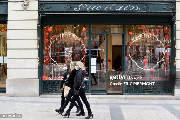 Women wearing mask walk past a Guerlain boutique on the Champs-Elyees avenue in Paris on May 11, 2020 on the first day of France's easing of lockdown...