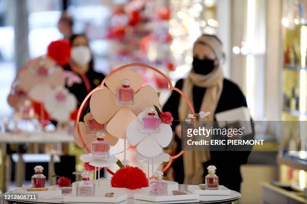 Clients wearing mask walk in a Guerlain boutique on the Champs-Elyees avenue in Paris on May 11, 2020 on the first day of France's easing of lockdown...