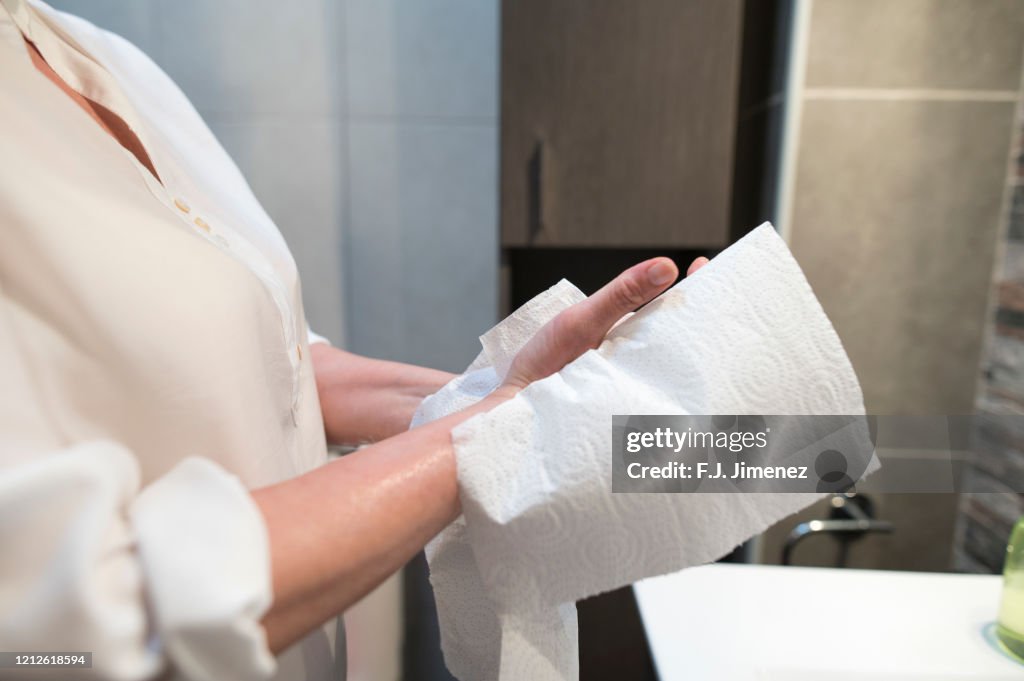 Close-up of woman drying her hands with paper