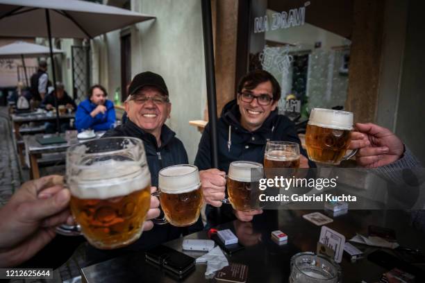 People drink beer at an outdoor seating section of a pub, as the Czech government lifted more restrictions allowing restaurants with outdoor areas to...