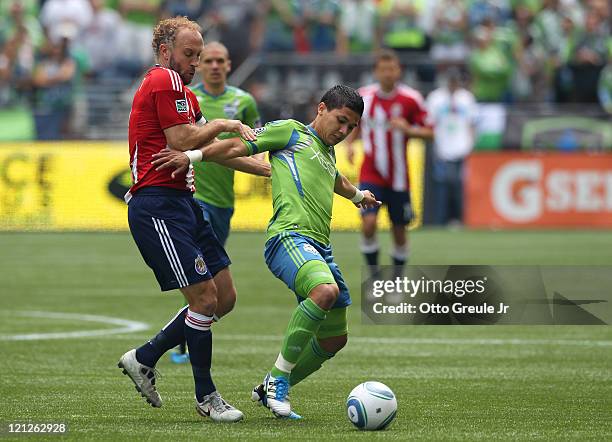 Fredy Montero of the Seattle Sounders FC battles Simon Elliott of Chivas USA at CenturyLink Field on August 13, 2011 in Seattle, Washington.