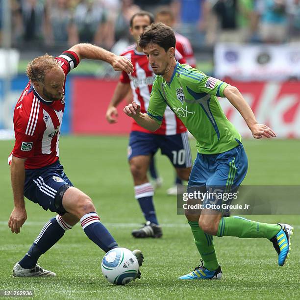 Alvaro Fernandez of the Seattle Sounders FC dribbles against Simon Elliott of Chivas USA at CenturyLink Field on August 13, 2011 in Seattle,...